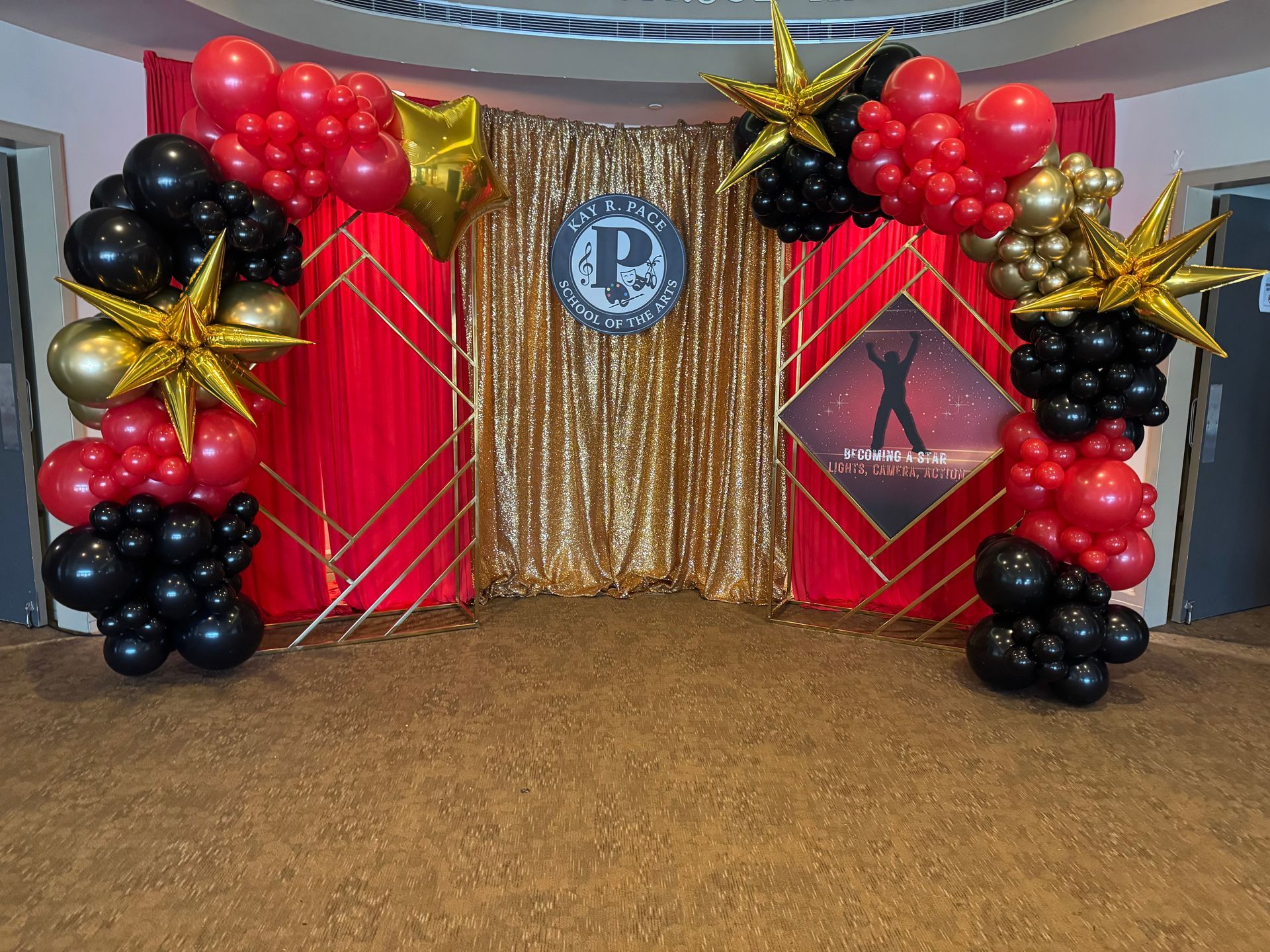 Red black and gold Hollywood themed balloon backdrop with gold sequin curtain and star accents for gala or awards night