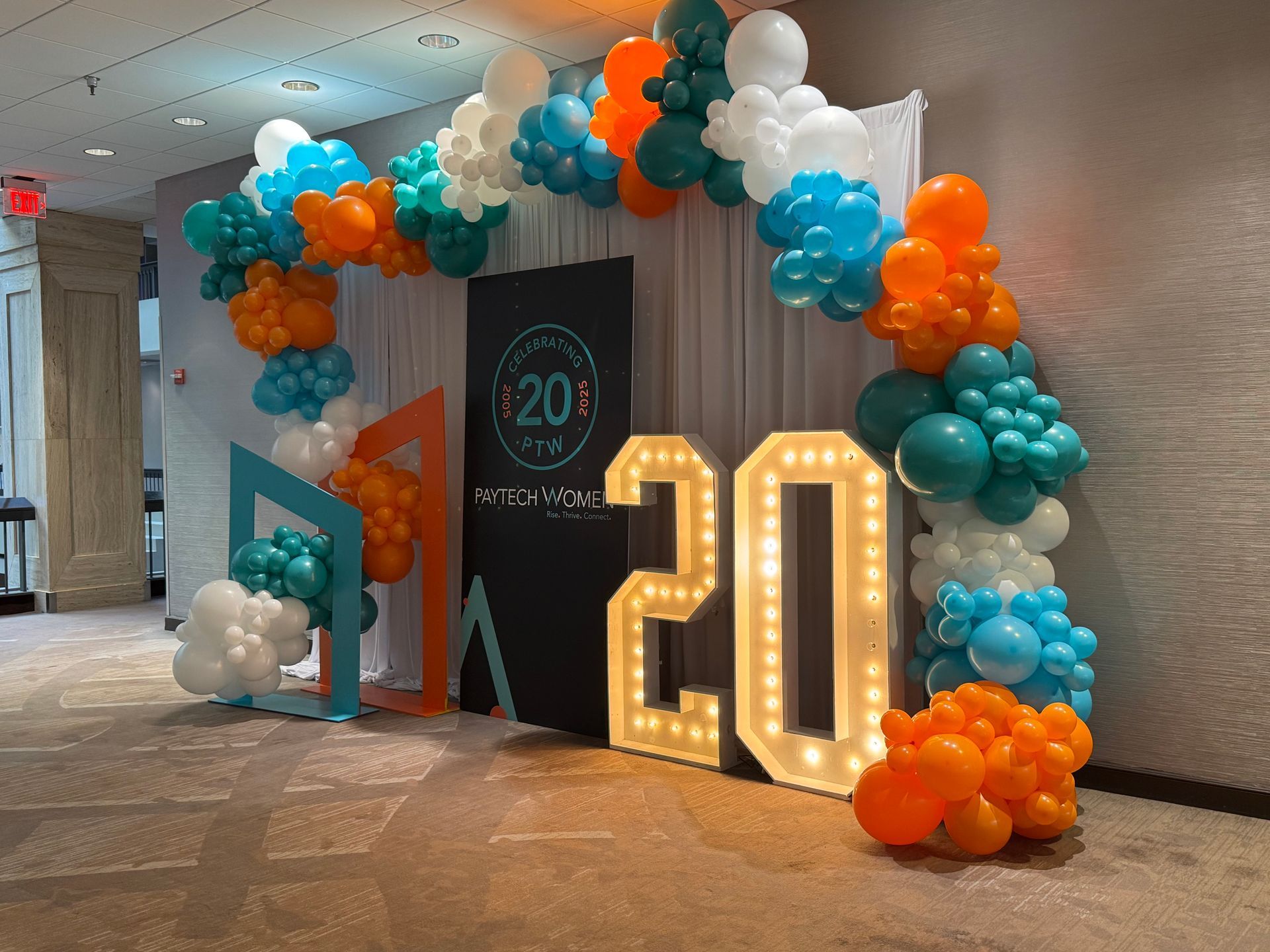 Teal orange and white balloon arch with marquee numbers for modern 20th birthday or anniversary party