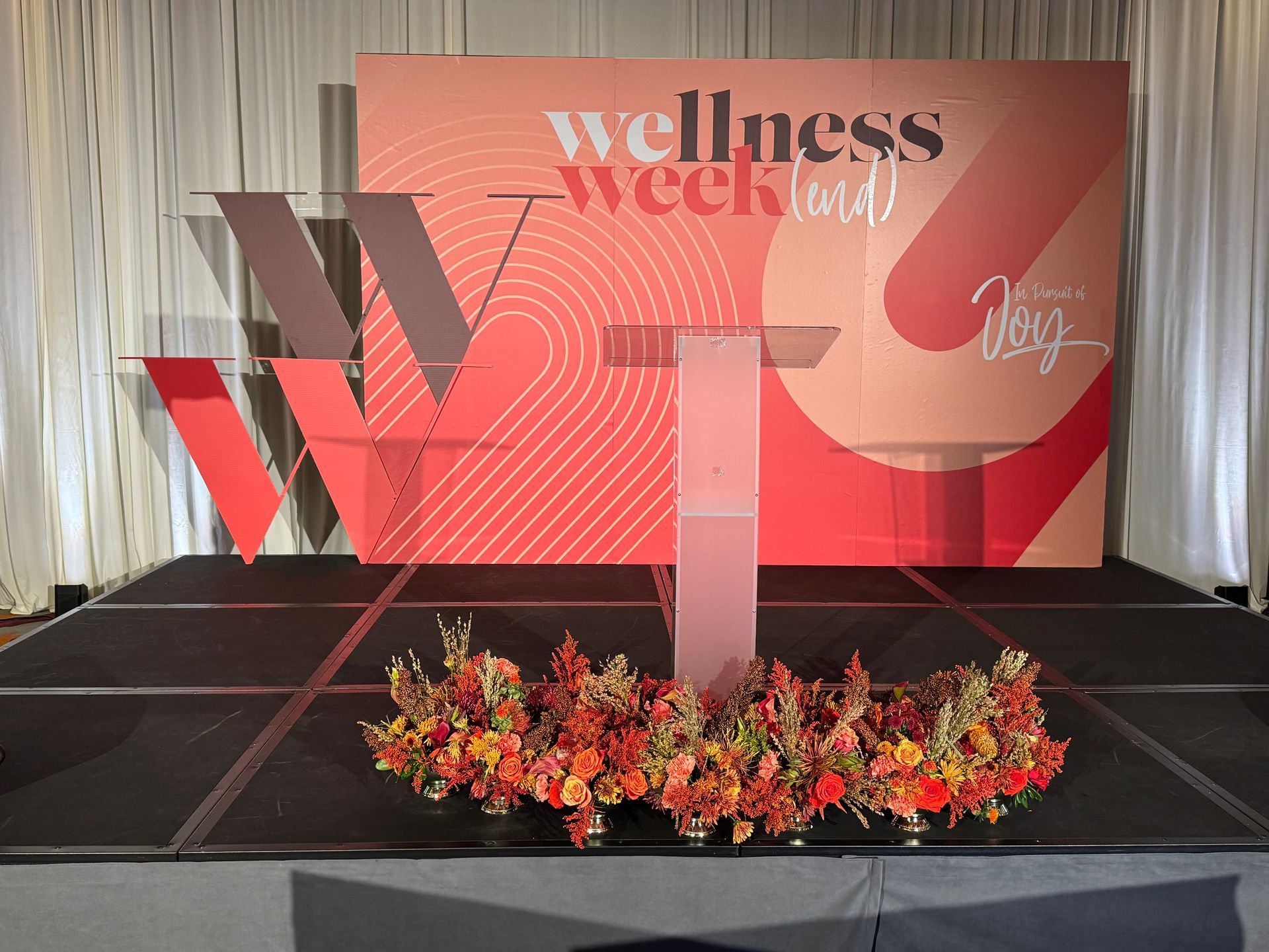 Large stage backdrop with red wellness week graphics and podium setup for corporate or wellness conference event