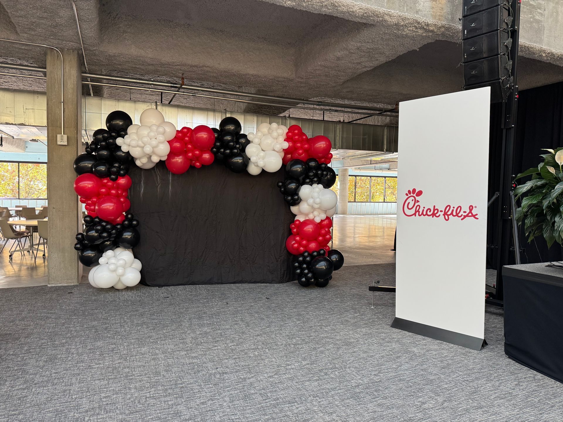Red black and white balloon photo backdrop with branded signage for grand opening or company event