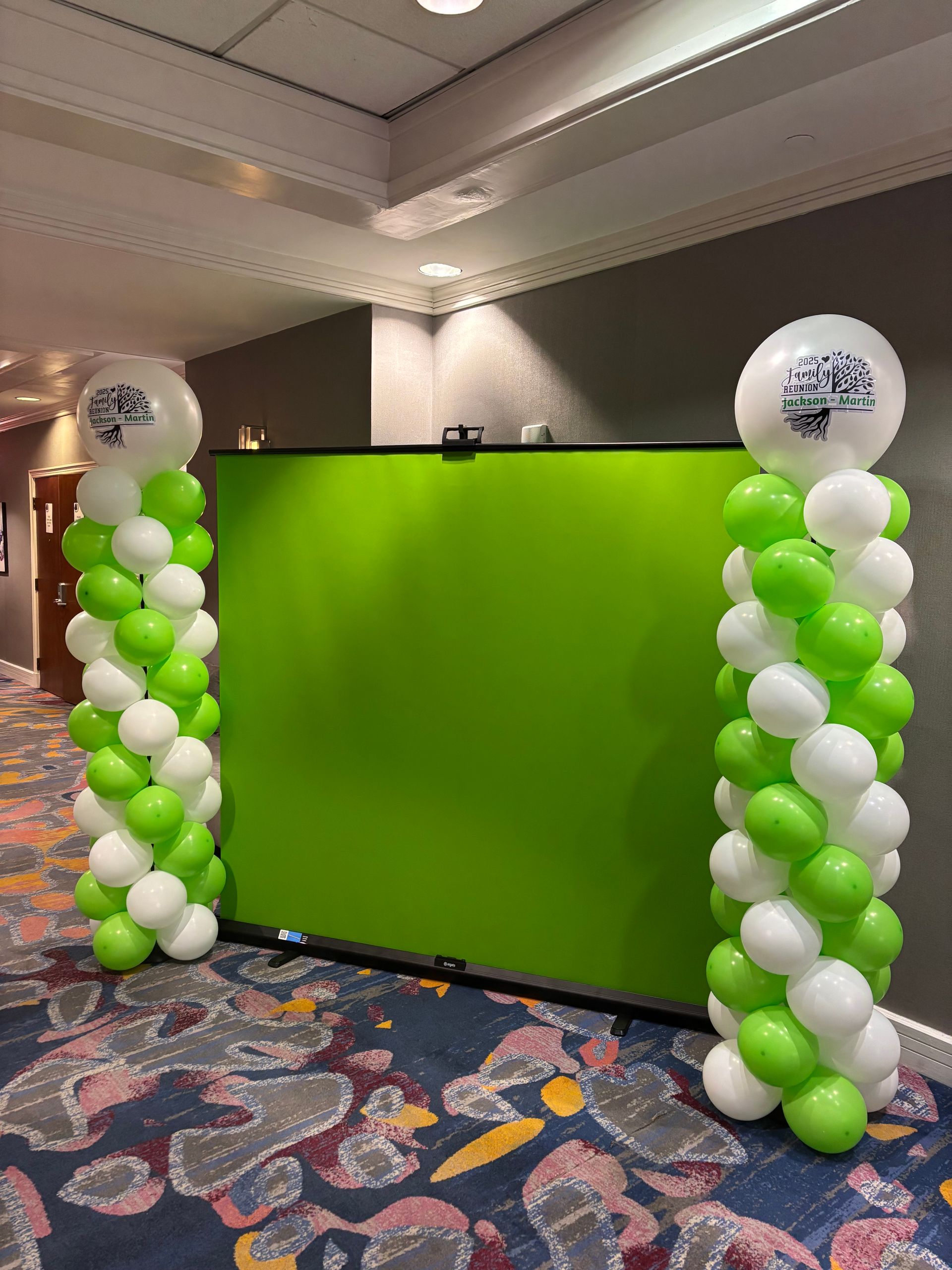 Green and white balloon columns with branded topper balloons framing an event display area