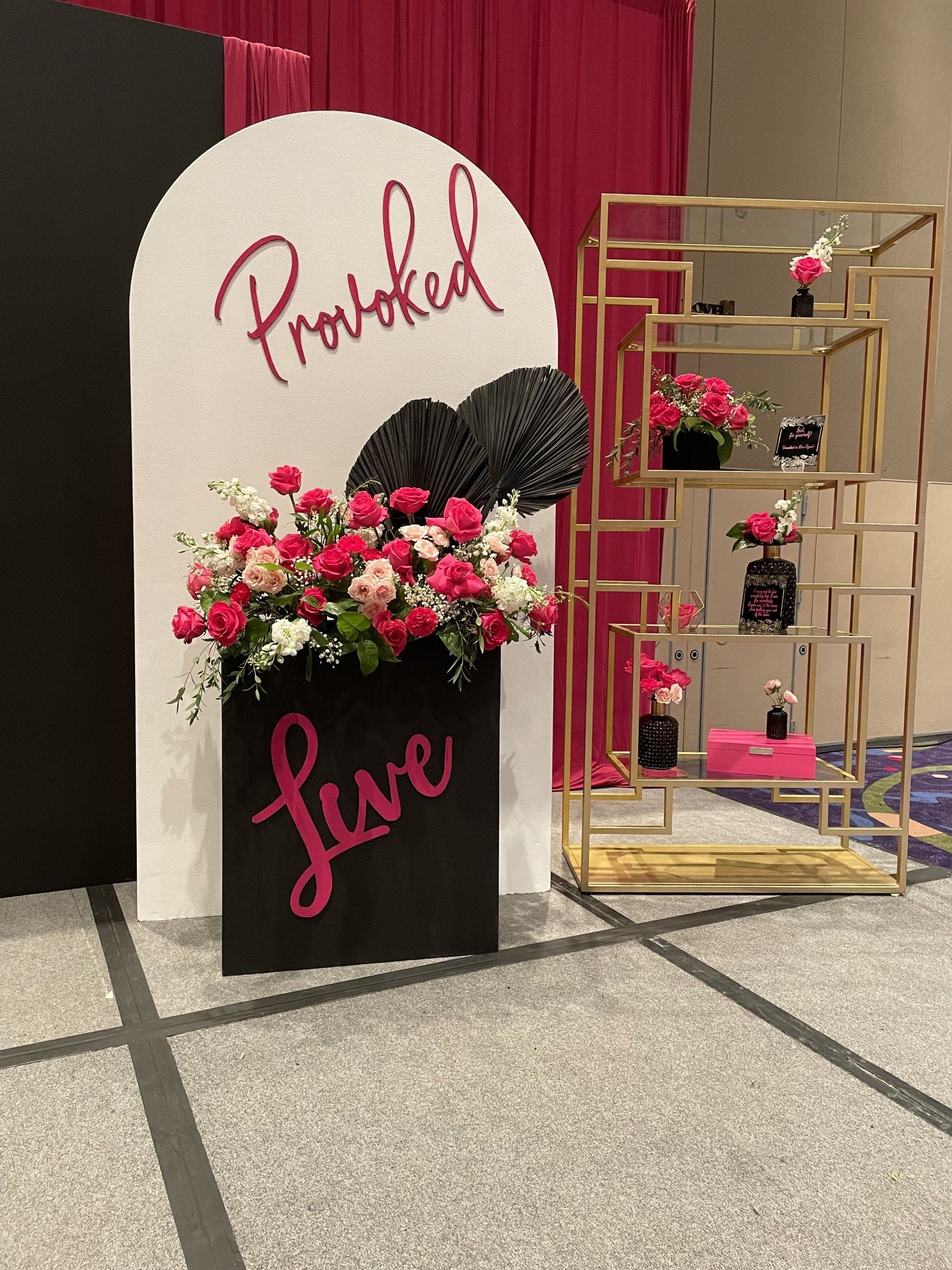 Floral décor and gold shelving styled around a custom backdrop for an indoor event display
