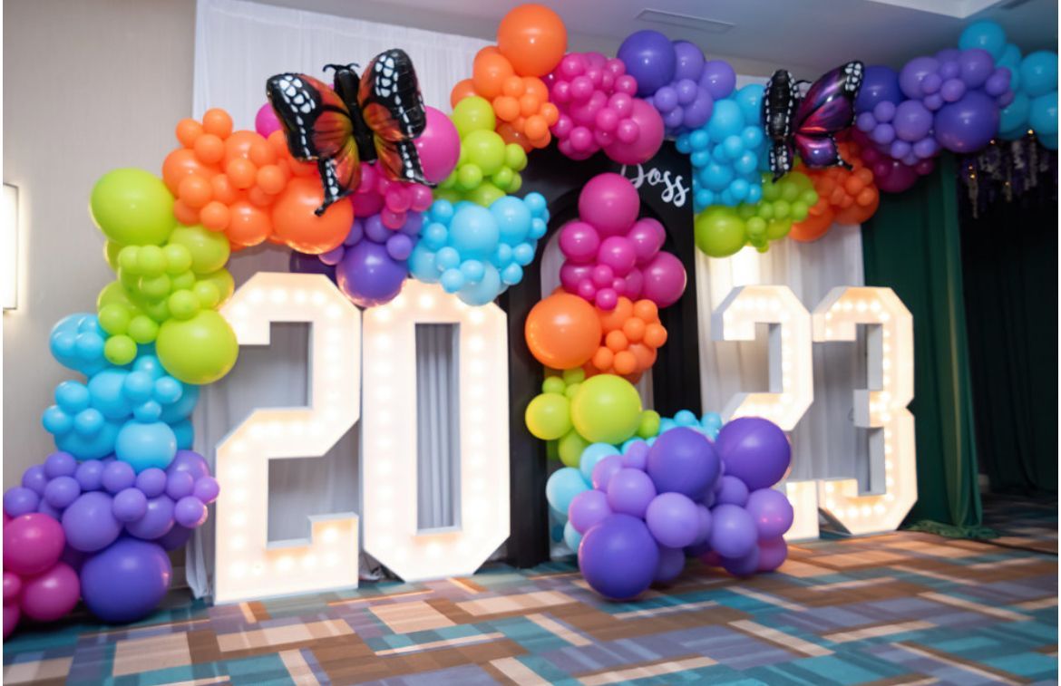 Colorful rainbow balloon arch with illuminated 2023 marquee numbers for graduation or New Year celebration