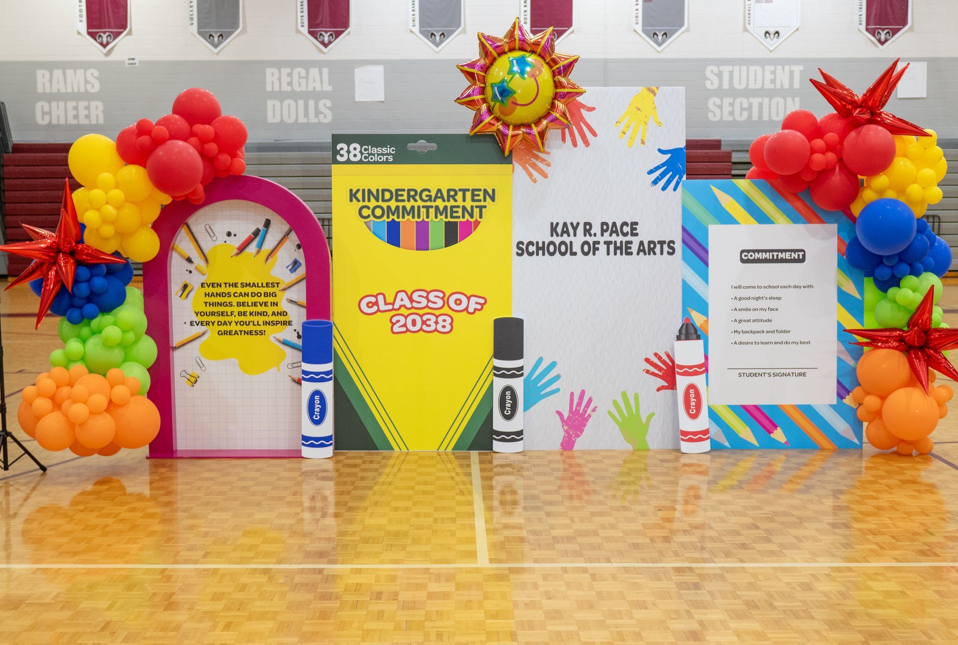 Kindergarten graduation themed school backdrop with crayons, books, and bright balloon decor for class celebration