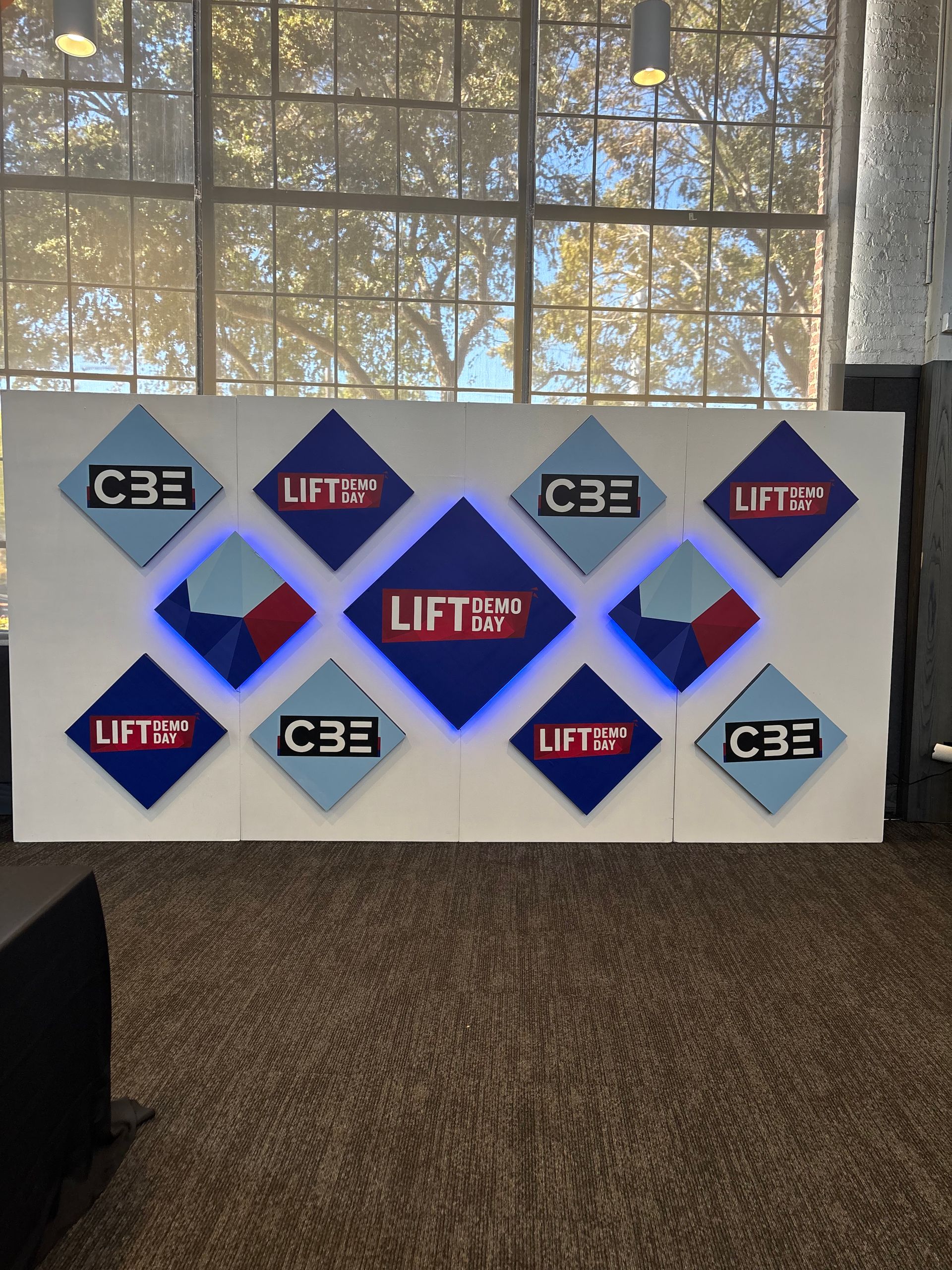 Modern corporate step and repeat backdrop with branded signage and large windows for conference or networking event photos