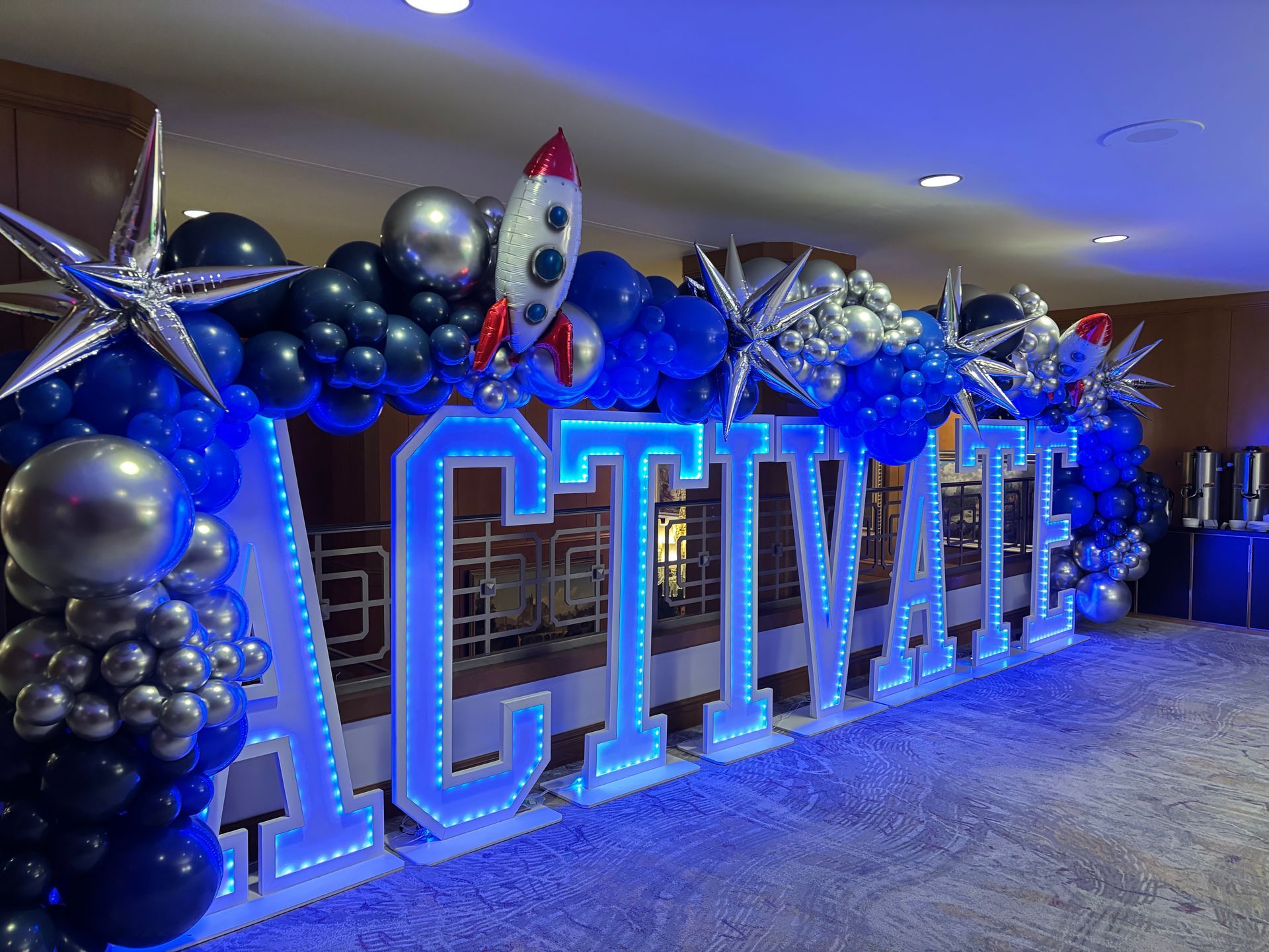Space themed balloon installation with rocket ships metallic balloons and marquee letters for kids party backdrop