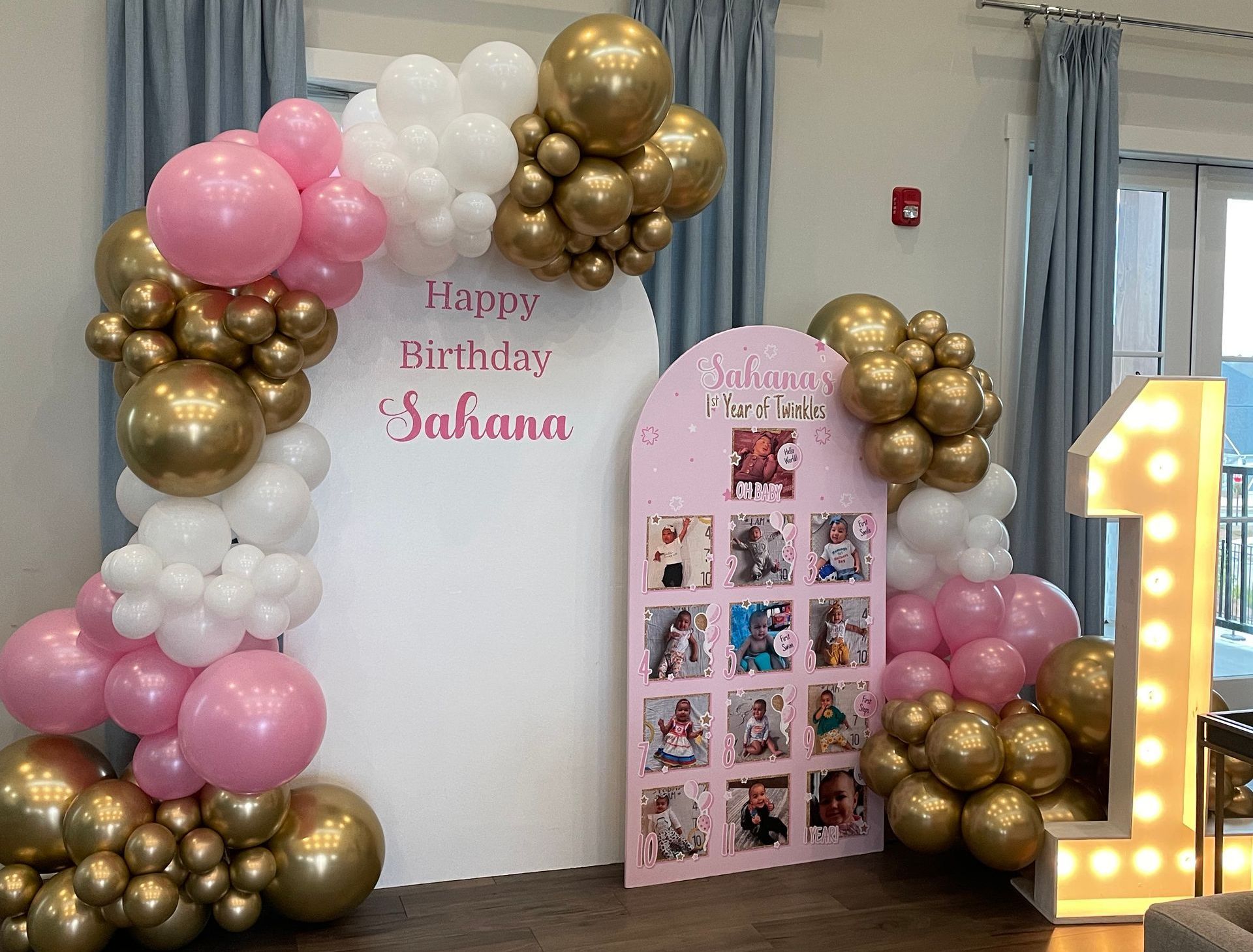 Pink white and gold balloon birthday backdrop with photo board and marquee number one for first birthday party