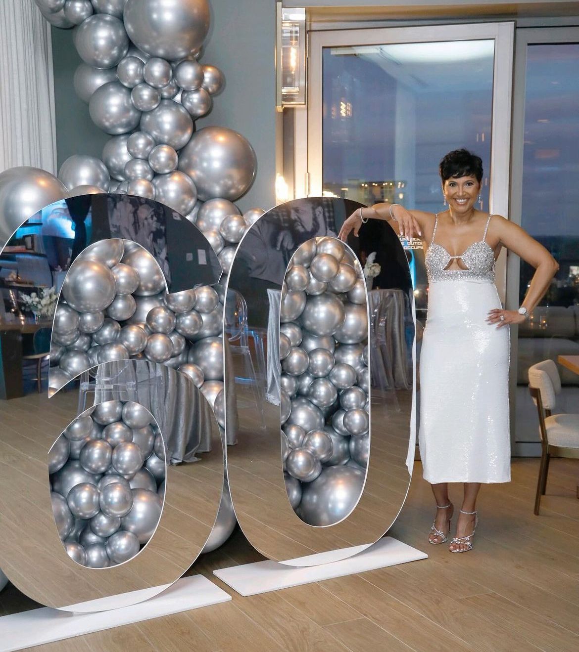 Silver balloon backdrop with metallic décor and luxury event setup with custom display tables