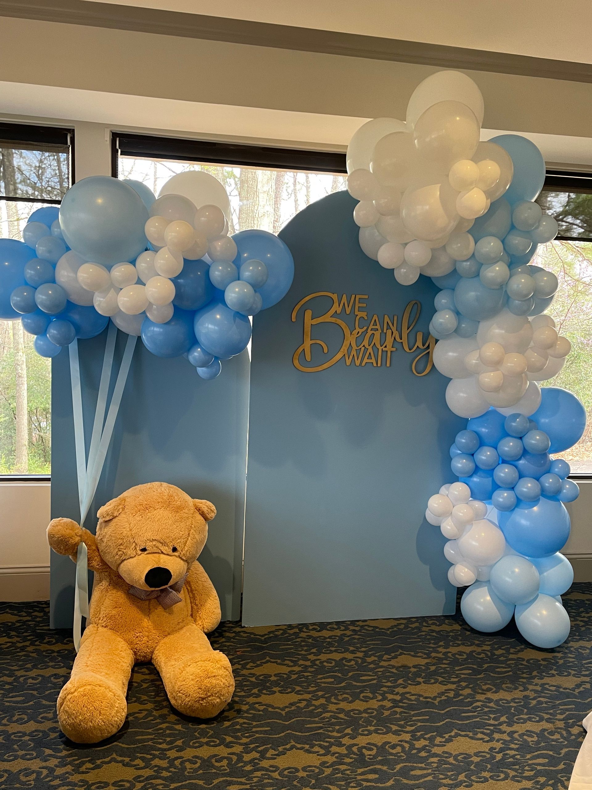 Blue and white balloon garlands with baby shower backdrop and custom sign for indoor celebration