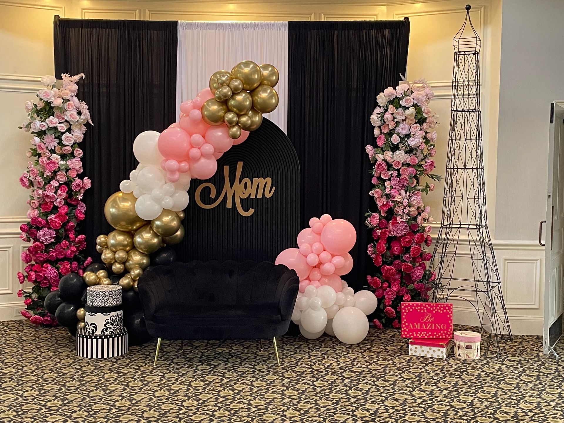 Elegant Mother’s Day themed balloon display with black gold blush balloons floral columns and lounge seating