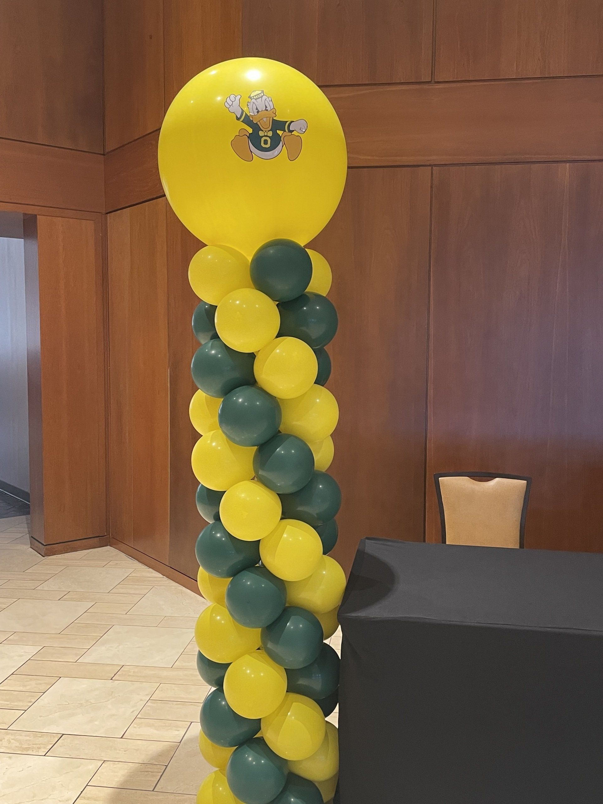 Yellow balloon column with green accents and themed character topper for a children’s event