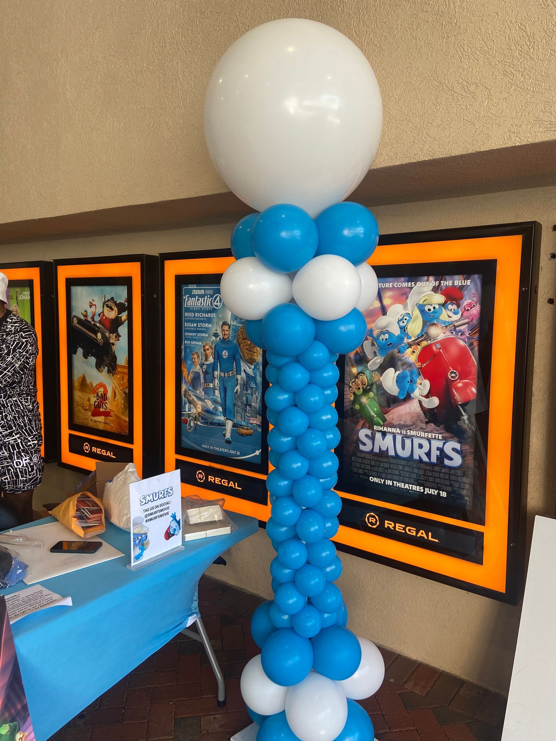 Blue and white balloon column with oversized white topper balloon inside an event venue