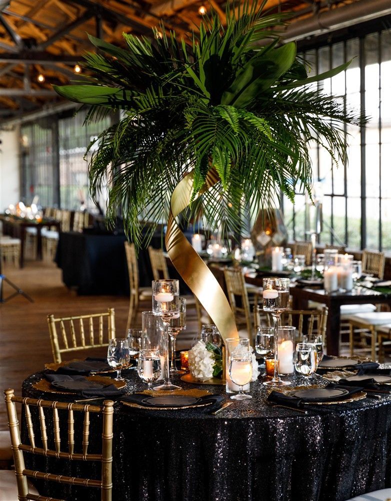 Lush tropical greenery centerpiece with palm leaves for elegant reception or gala décor