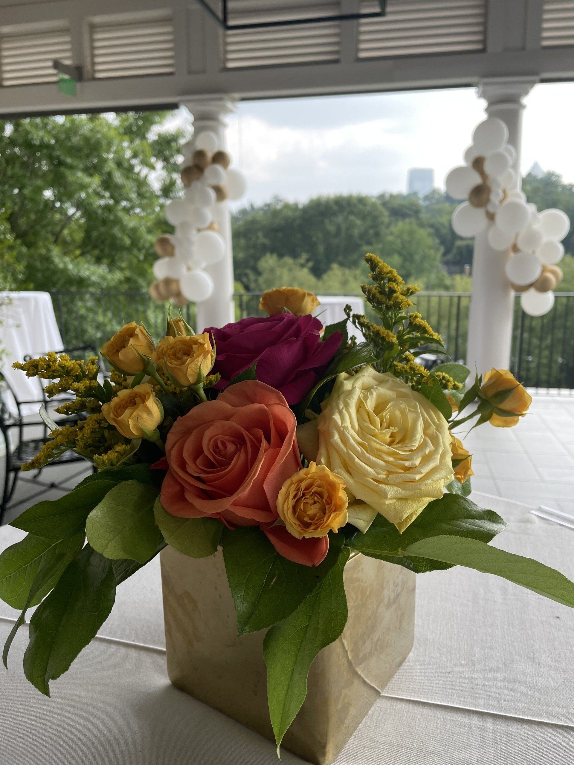 Outdoor balcony setup with white balloon garlands wrapped around columns and floral décor