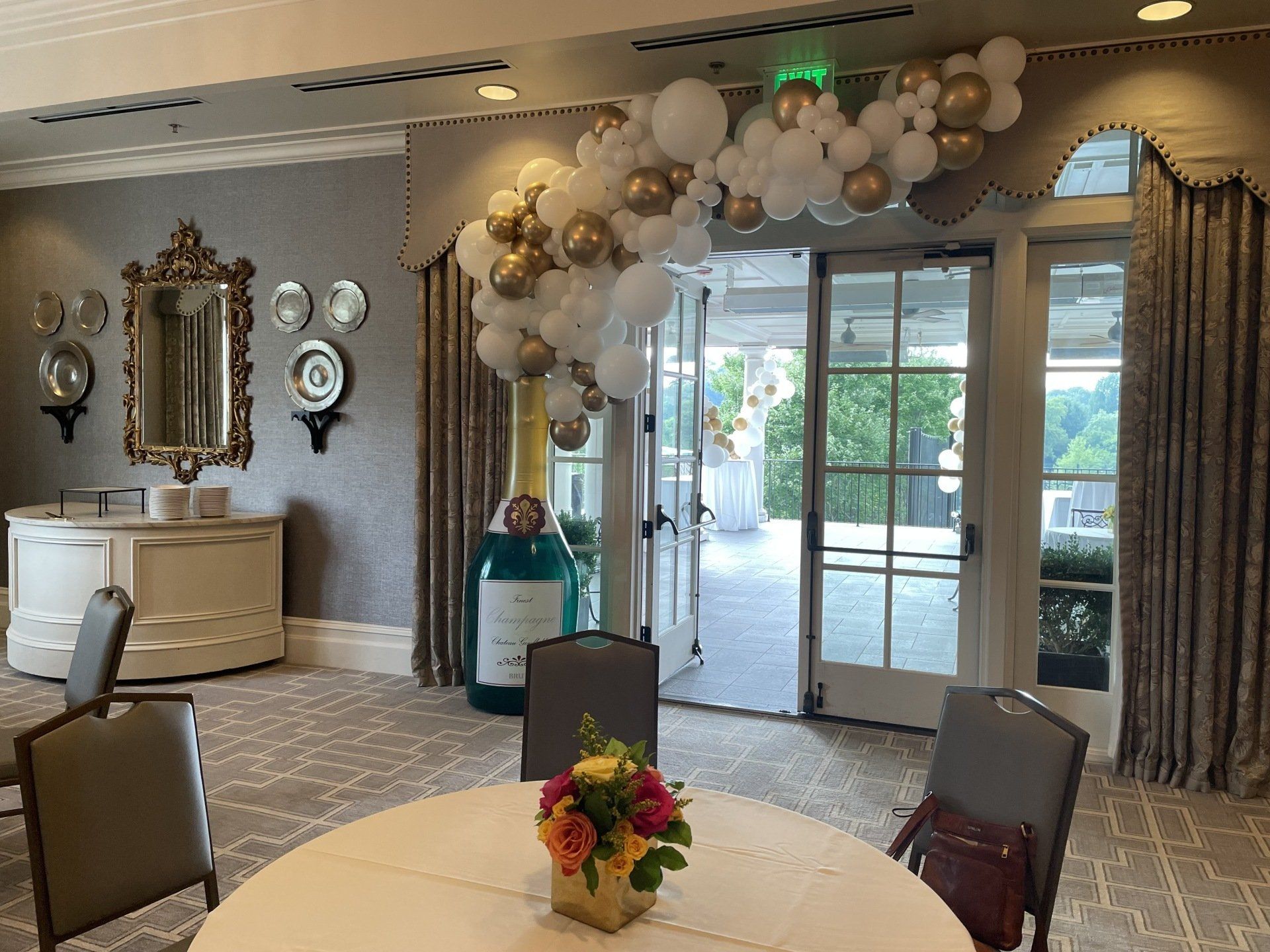 Neutral white and gold balloon garland around elegant event entrance with draped curtains