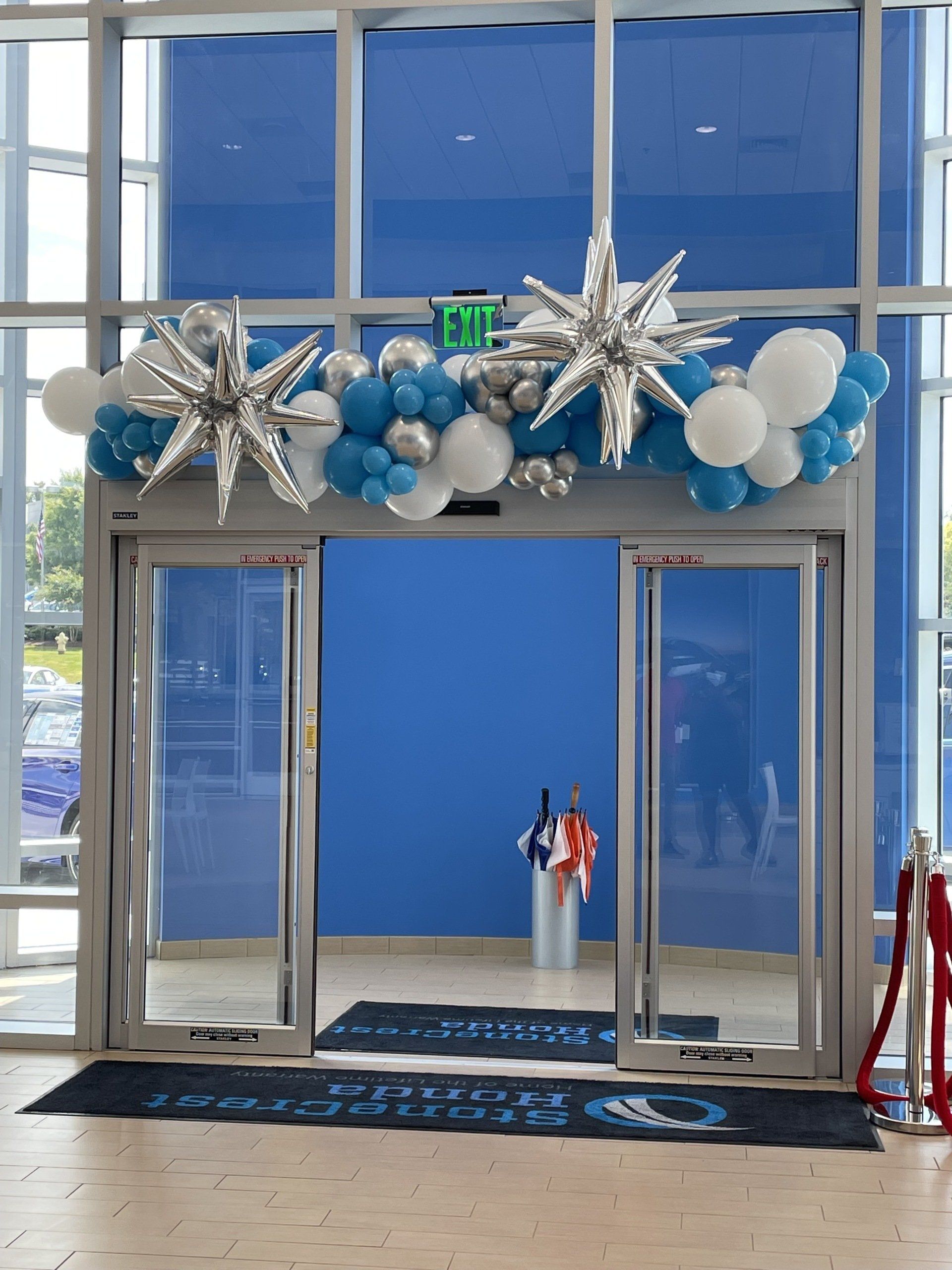 Blue white and silver balloon installation with metallic star balloons across indoor venue entrance