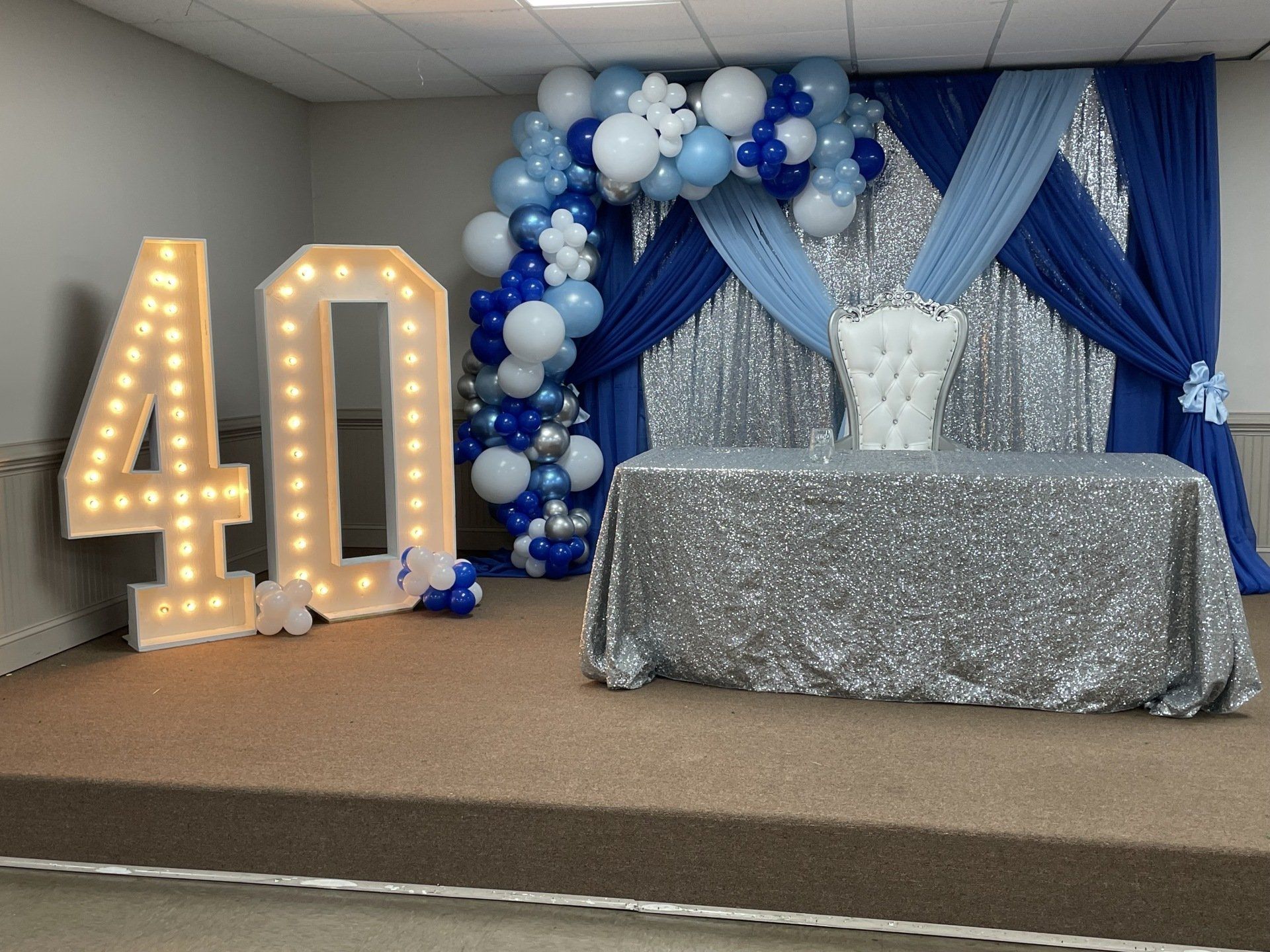 Royal blue and silver balloon backdrop with marquee number 40 for milestone birthday celebration