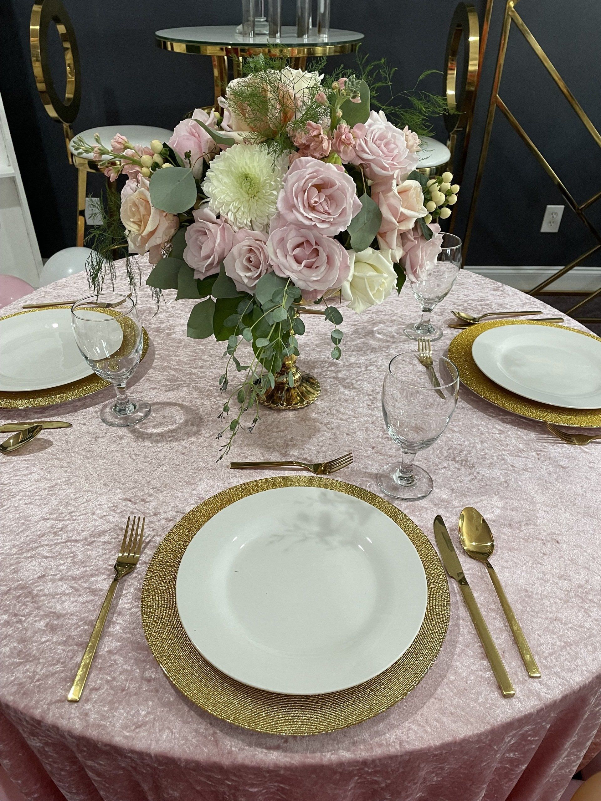 Blush pink and white rose centerpiece with greenery on an elegant dining table setting