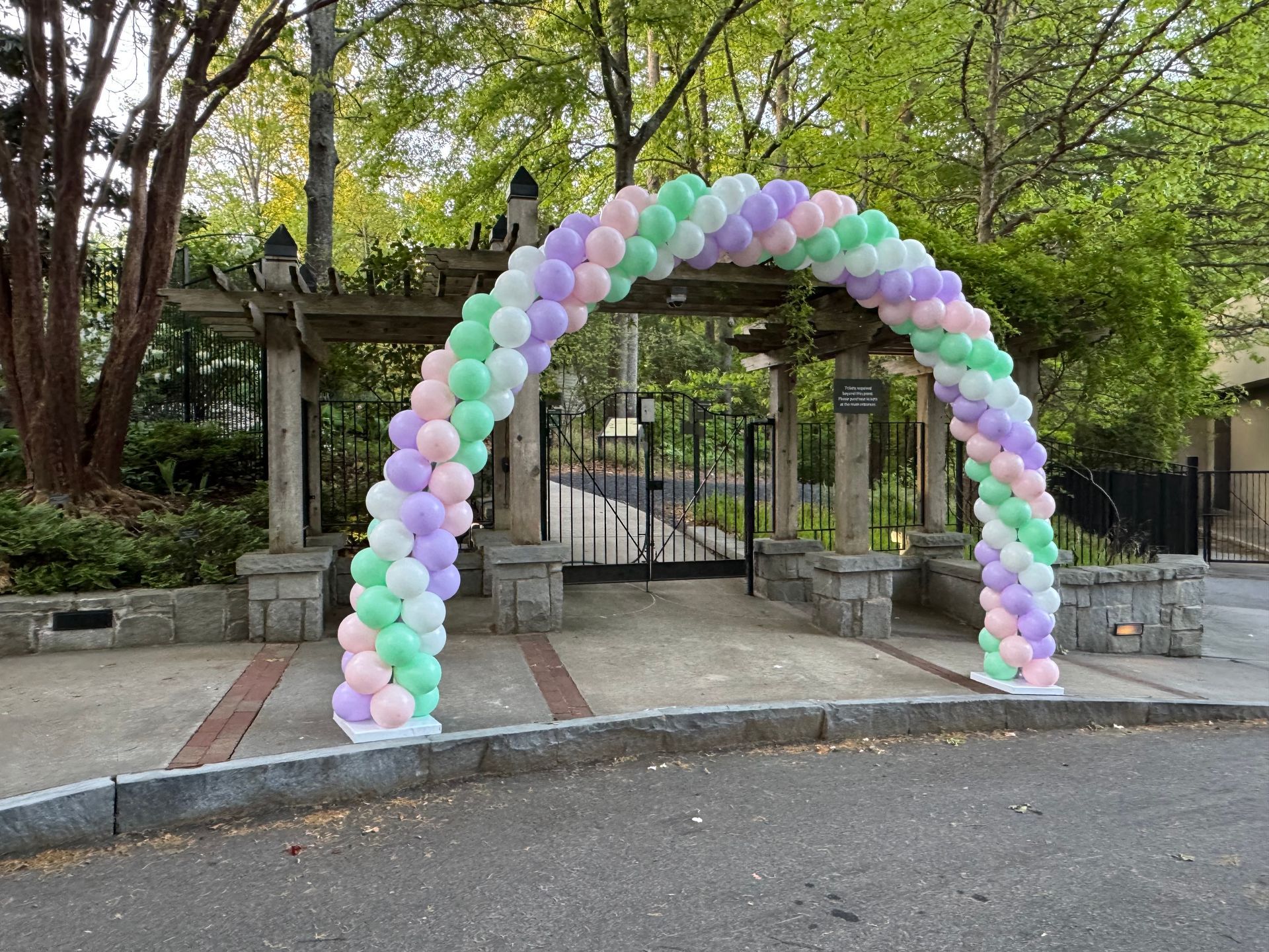 Pastel balloon arch outdoor entrance setup for a garden or courtyard event