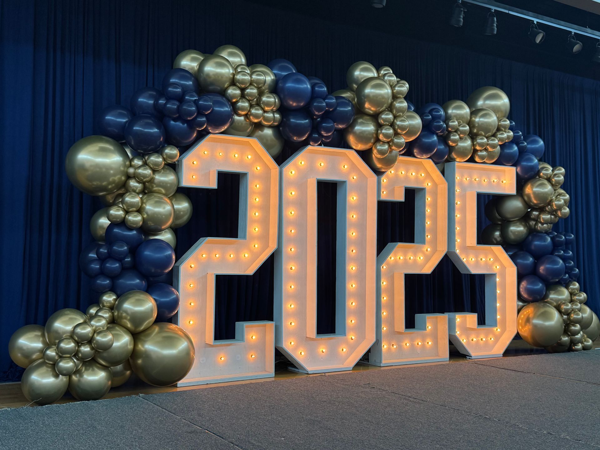 Blue and gold balloon arch with large marquee 2023 numbers for a graduation celebration
