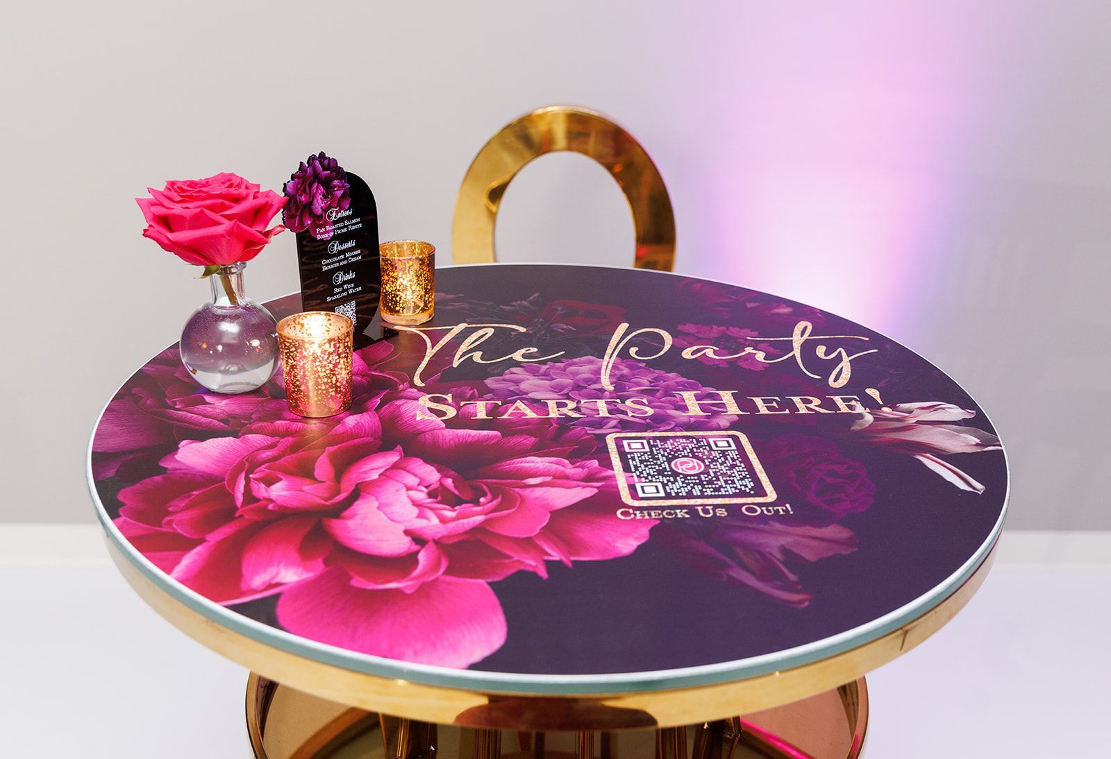 Round cocktail table with custom floral wrap, candles, and branded party décor styling for event lounge area