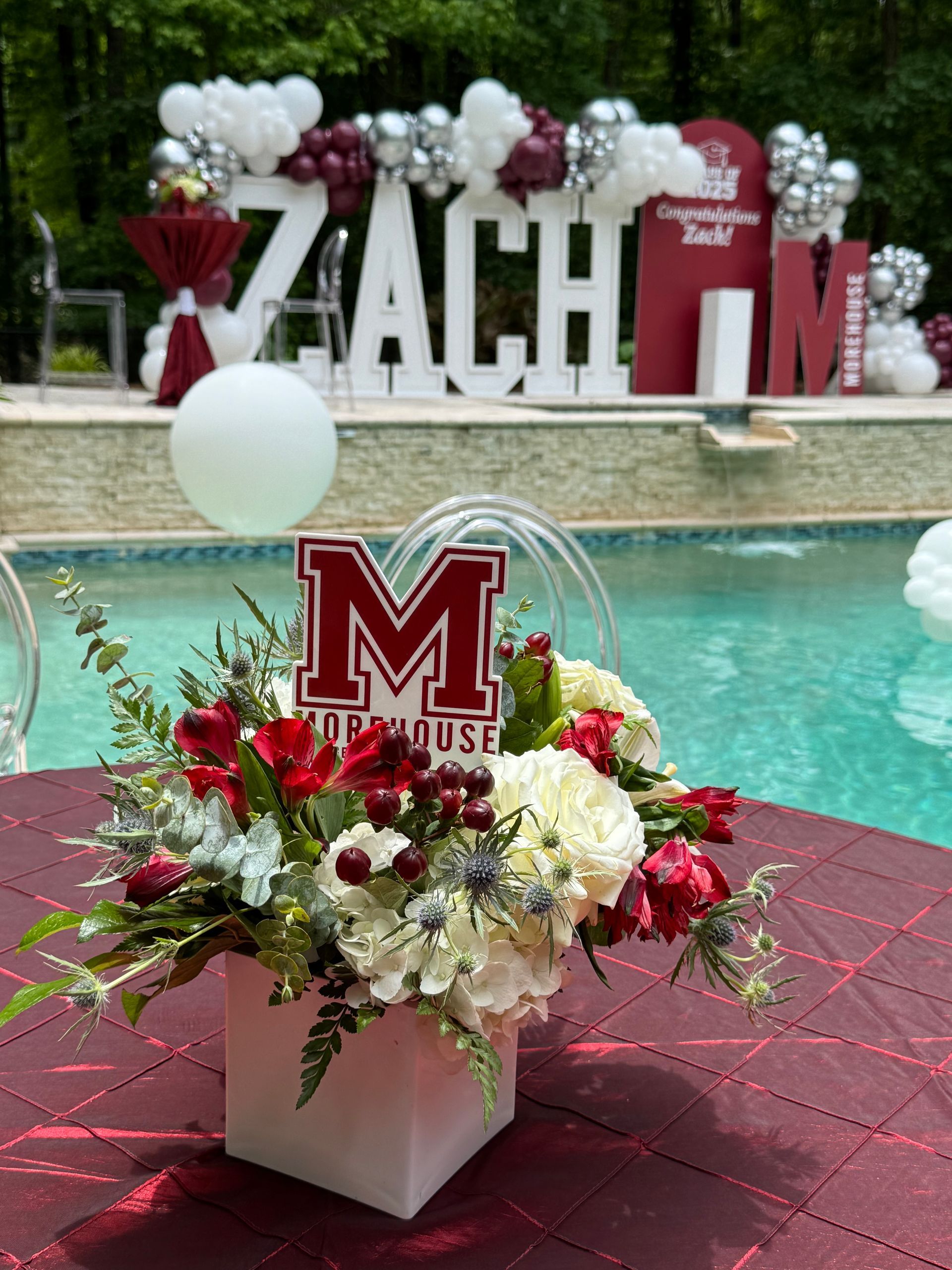 Maroon, white, and silver balloon décor surrounding large ZACH sign at an outdoor celebration