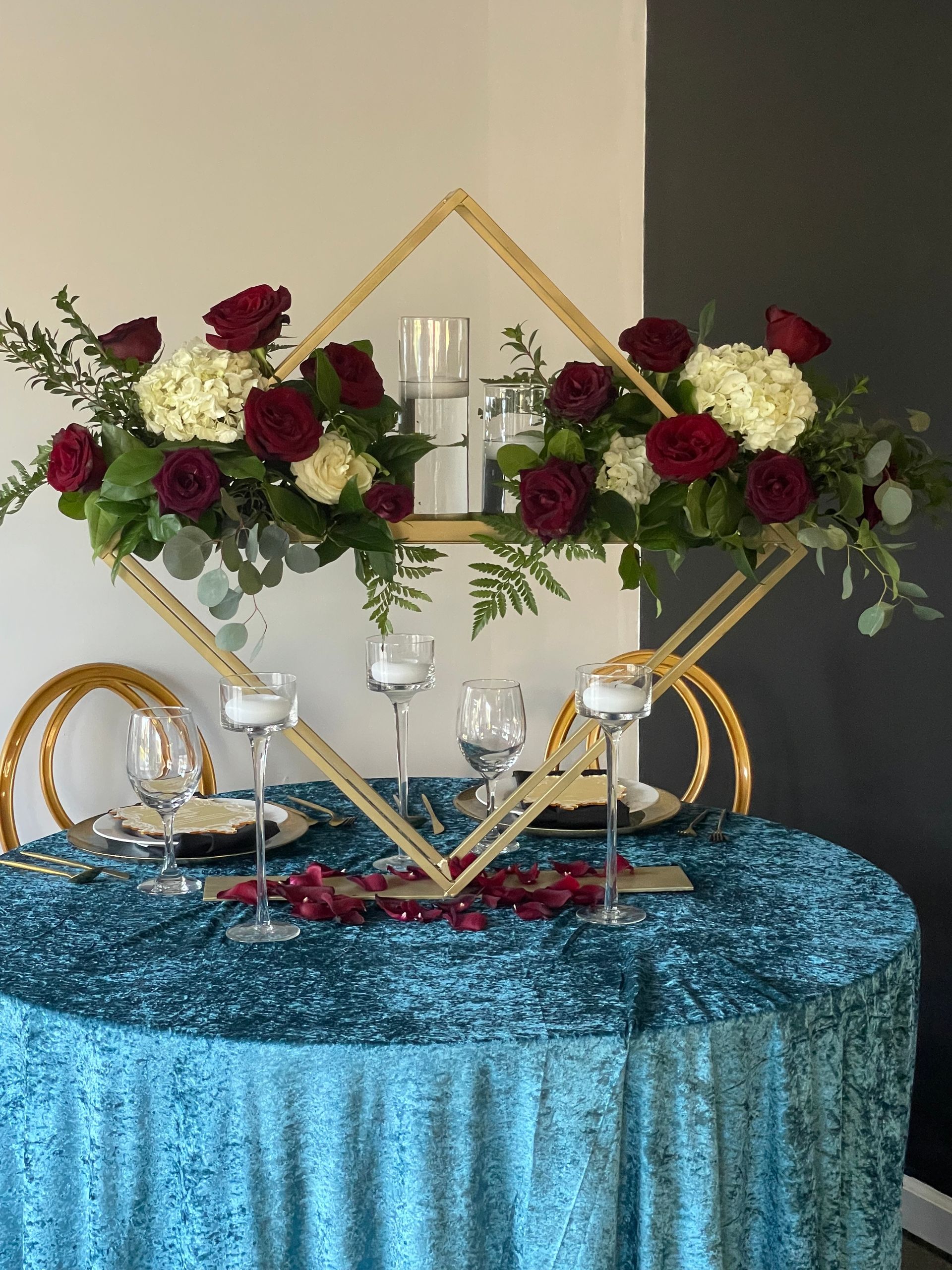 Red and white rose floral arrangements displayed on gold geometric stands