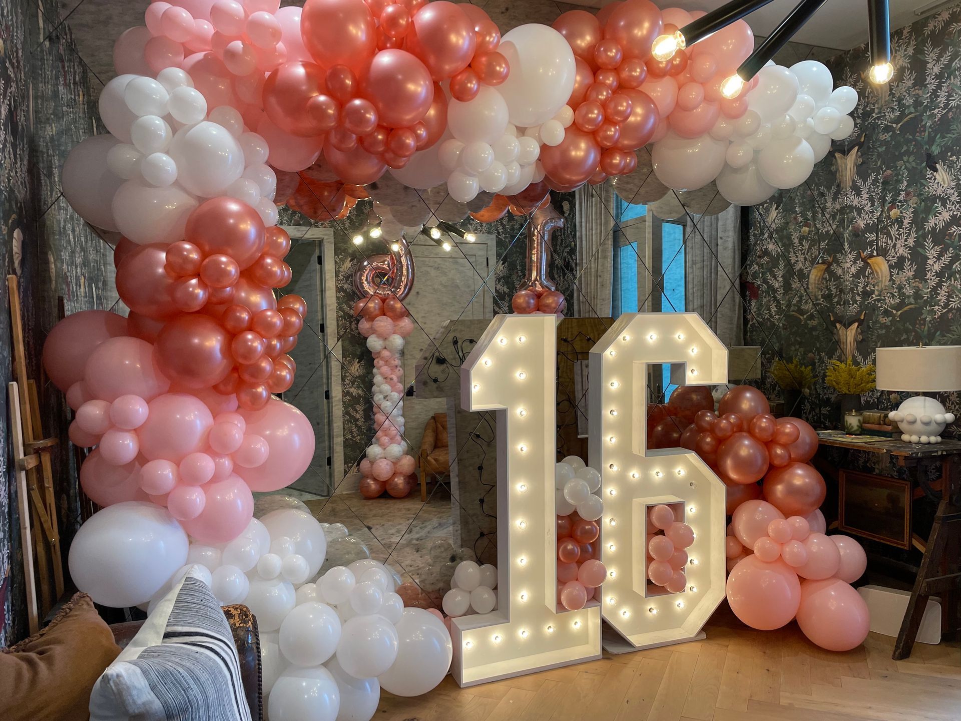 Blush and rose gold balloon arch with illuminated marquee number 16 for sweet sixteen birthday party backdrop