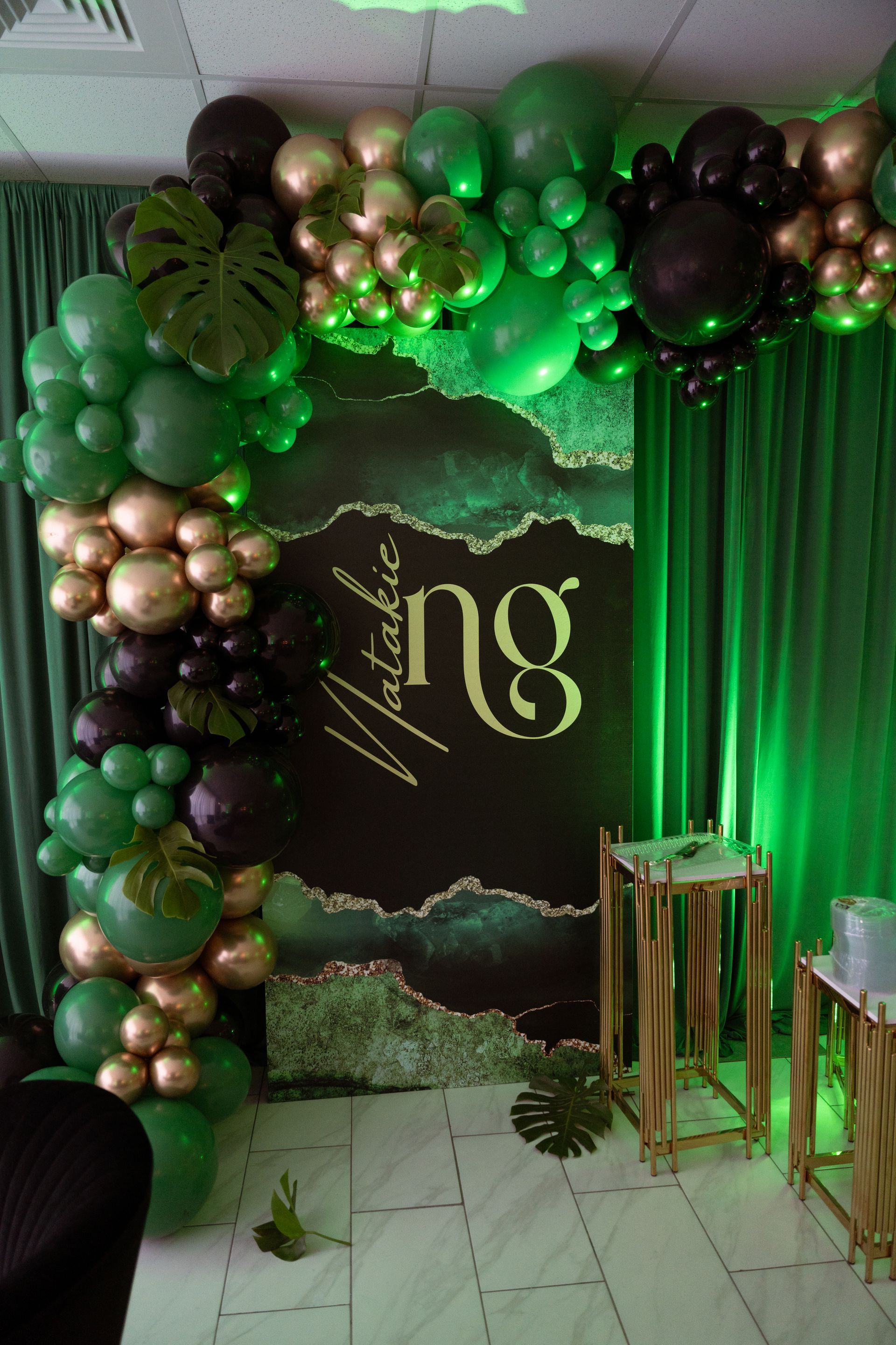 Emerald green black and rose gold balloon garland with monstera leaves and green sequin backdrop for luxury birthday