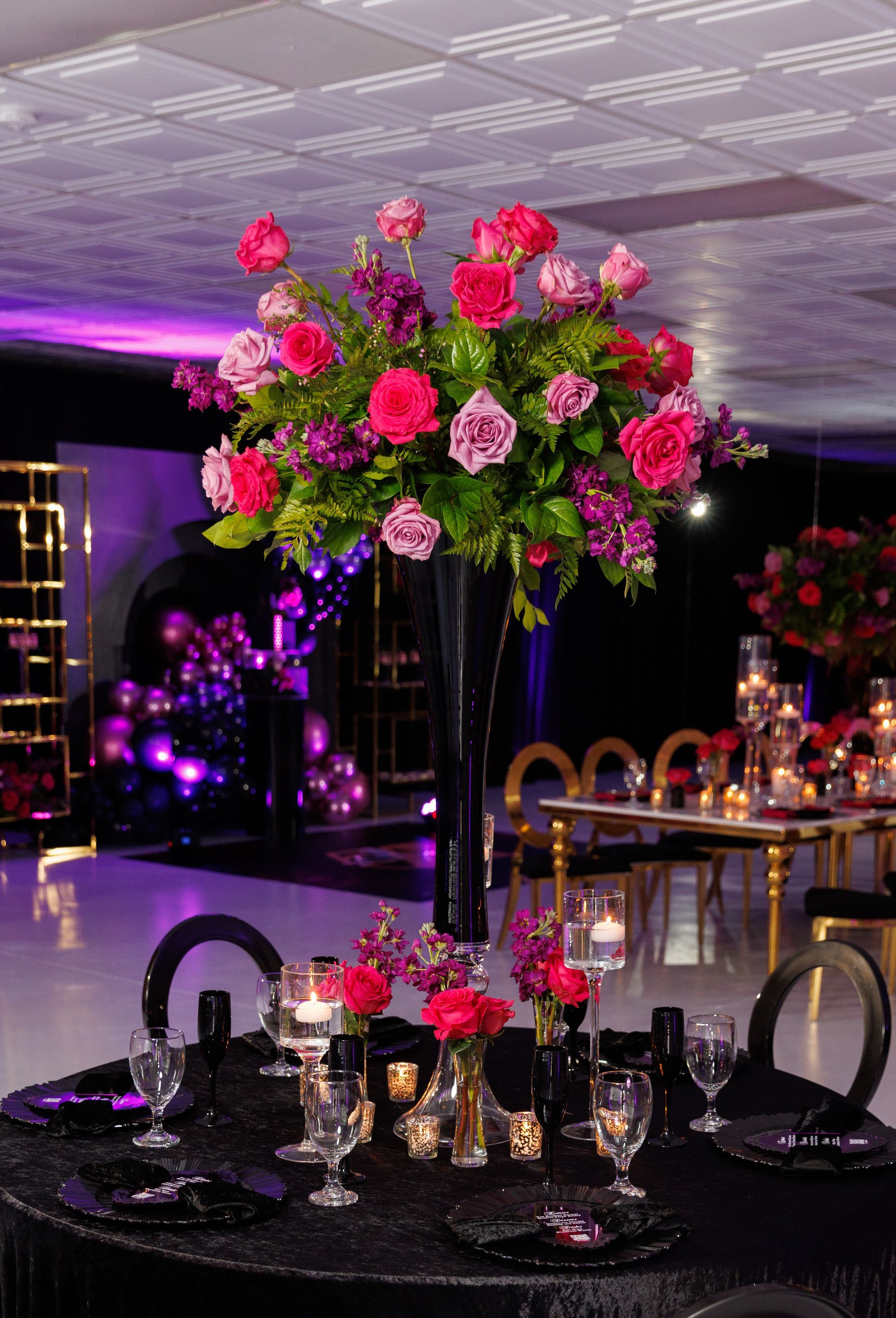 Tall pink and fuchsia rose floral centerpiece with greenery for elegant wedding or gala event tables