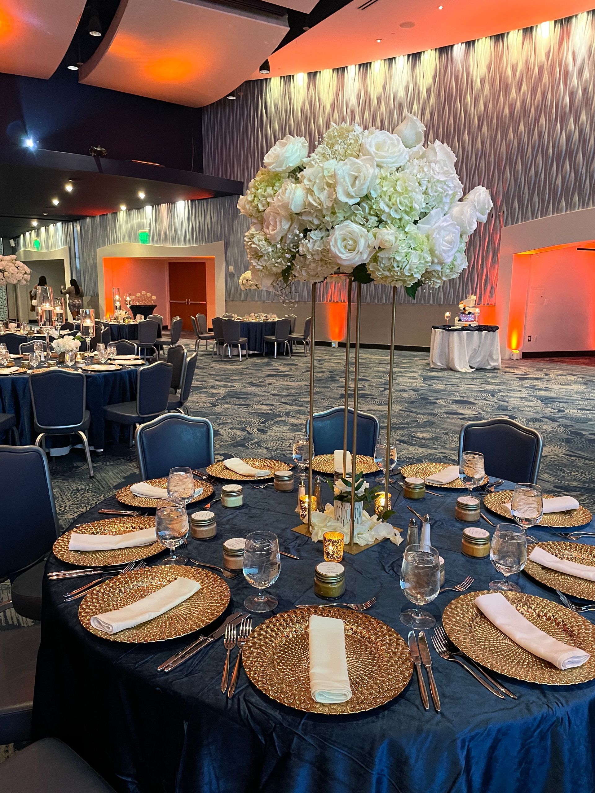 Large white floral centerpiece displayed on a tall stand inside an elegant event venue
