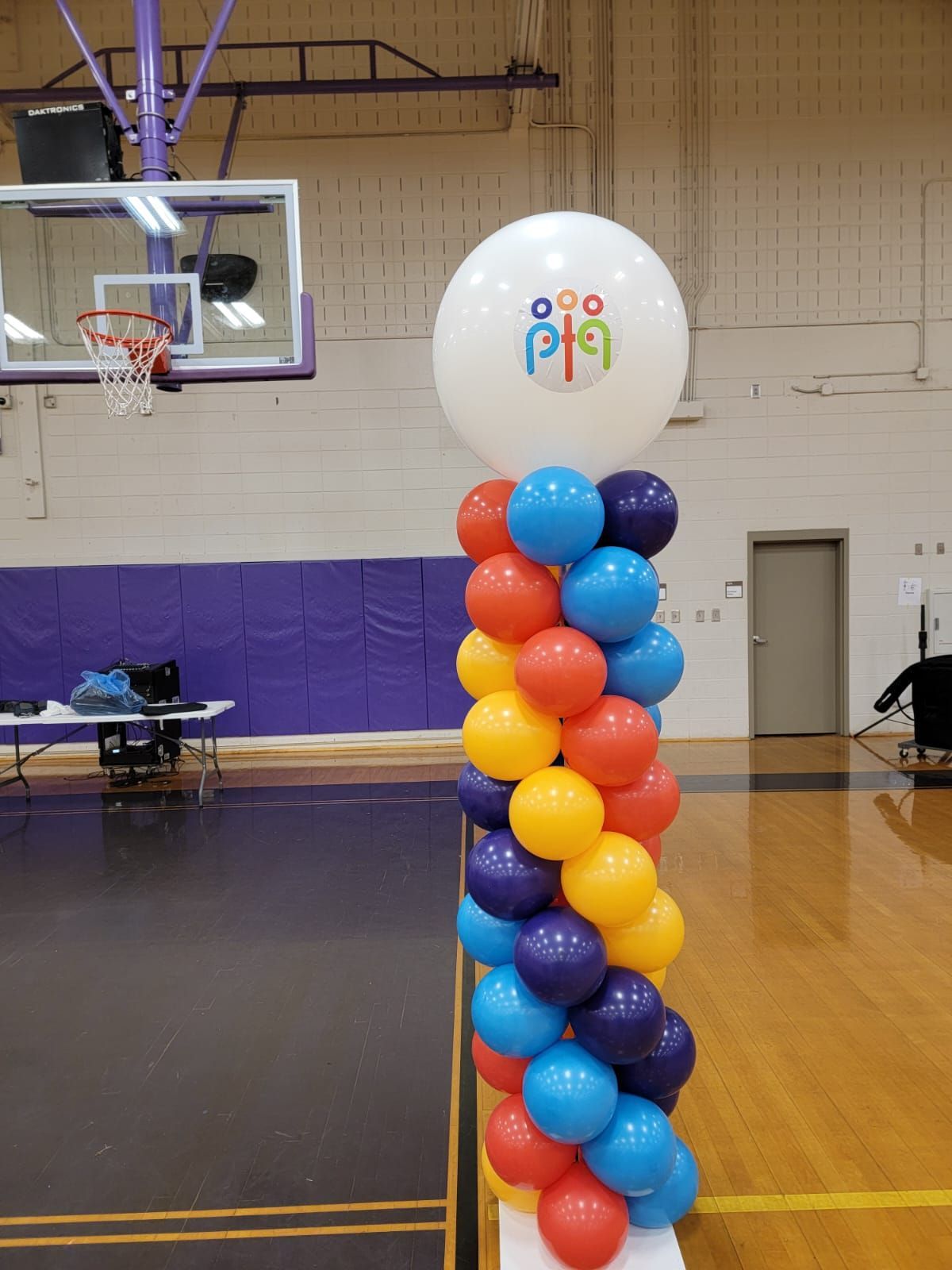 Red, white, and blue balloon column with branded topper balloon inside a school gym