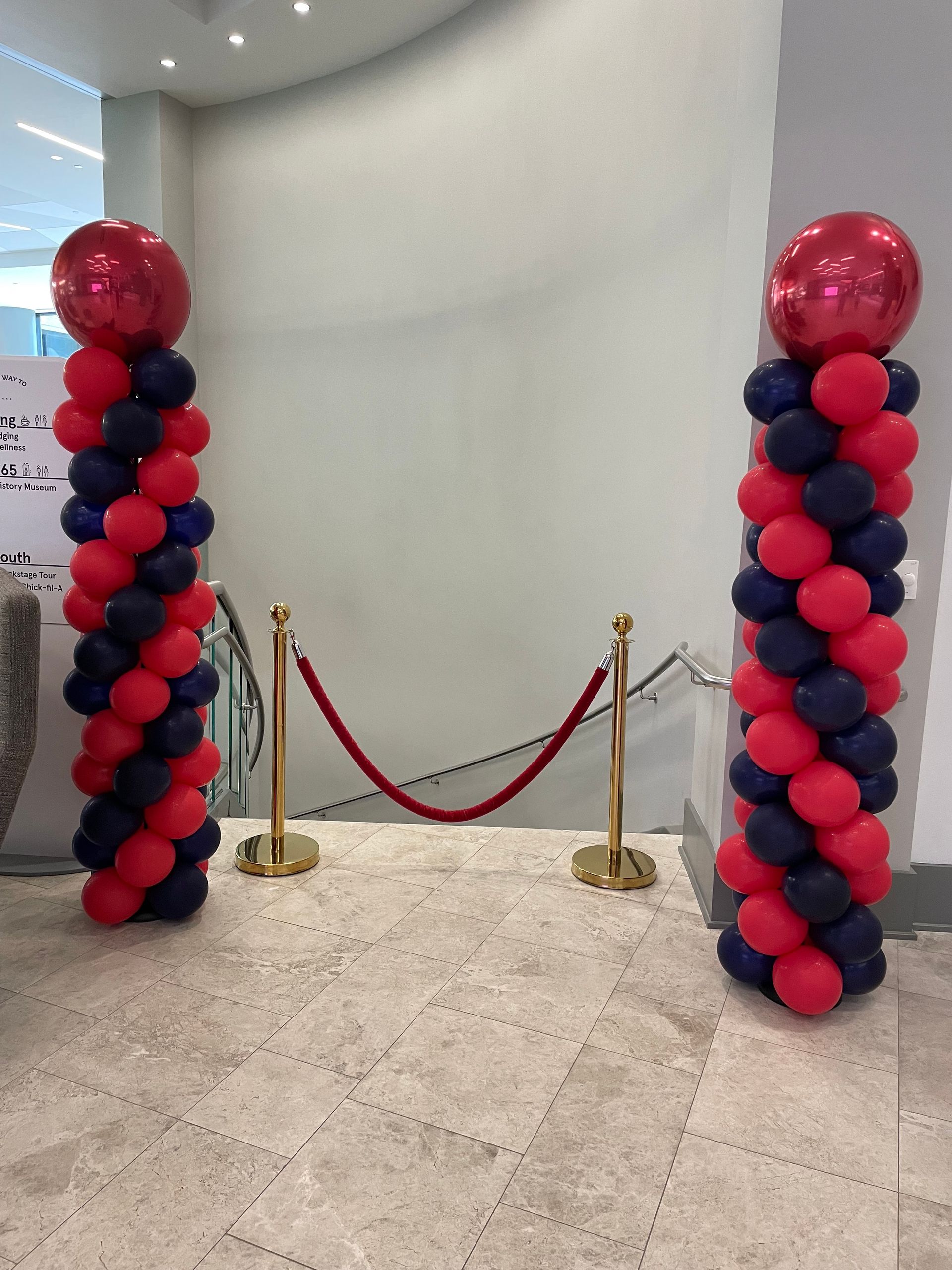 Red and navy balloon columns with glossy red topper balloons inside an event space