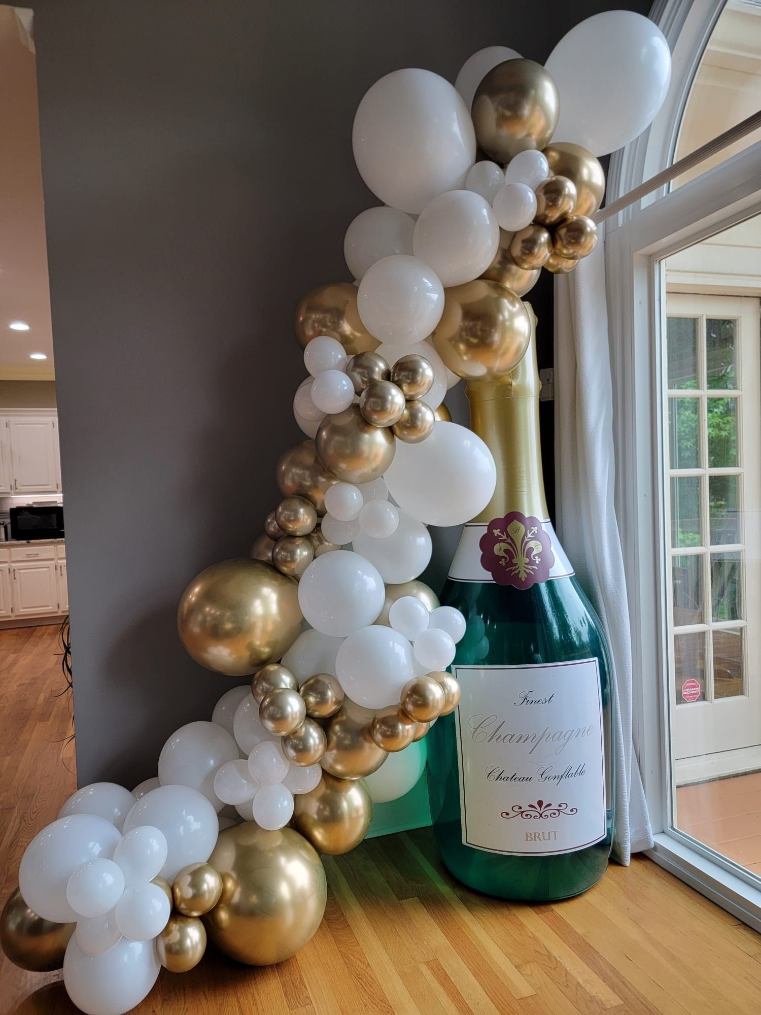 White and gold organic balloon column installed beside doorway for elegant indoor celebration