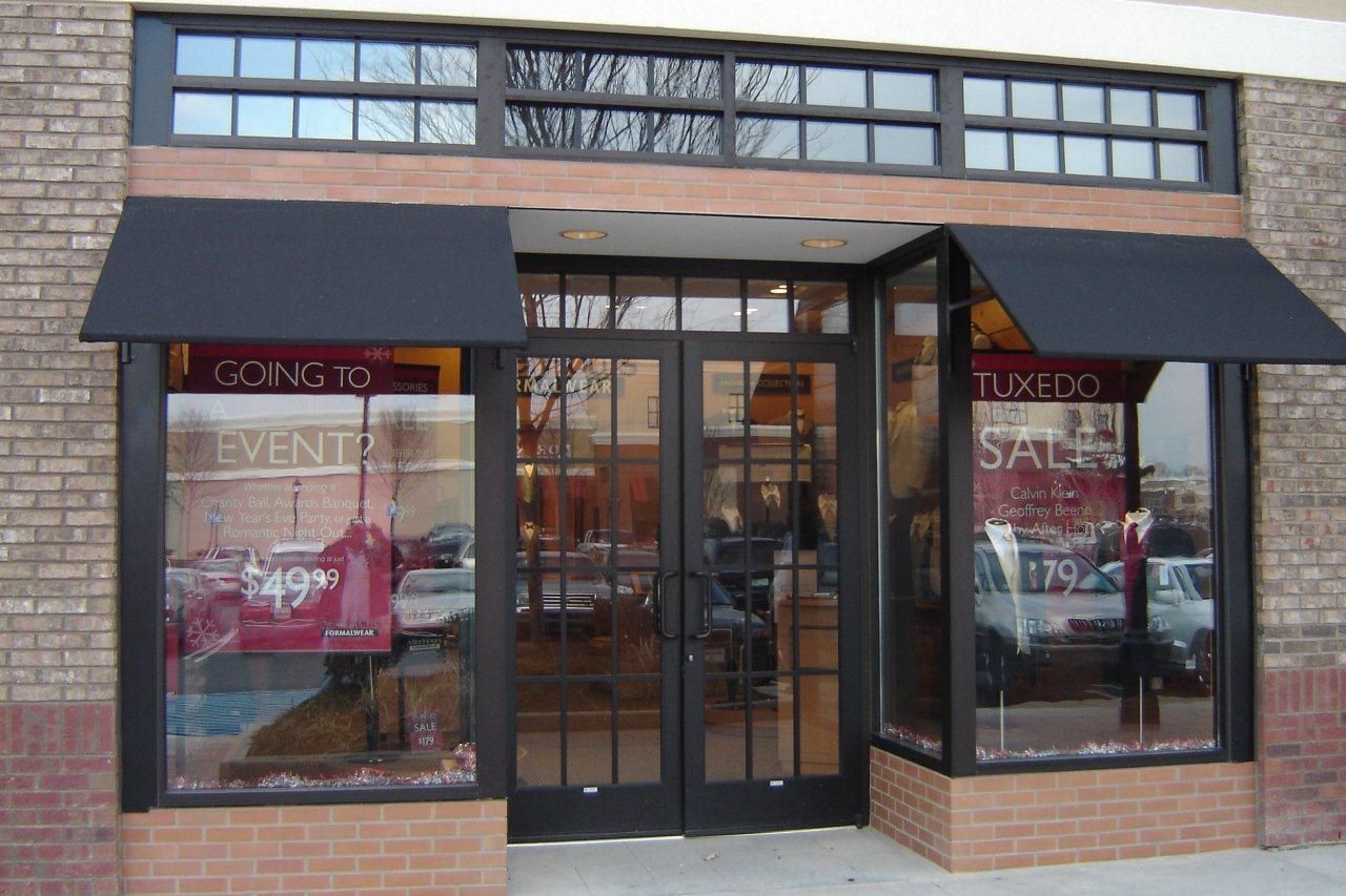 Storefront with black awnings, windows, and a brick facade. Displays in windows show