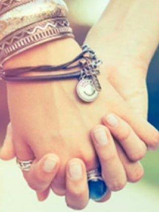 Two hands holding together, with bracelets and rings visible at Enlightened Life Temple