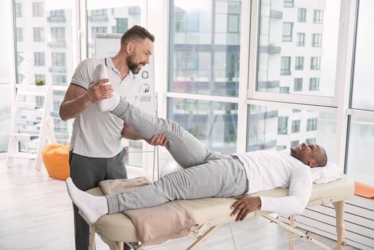 Physical therapist stretching a patient's leg in a bright clinic room