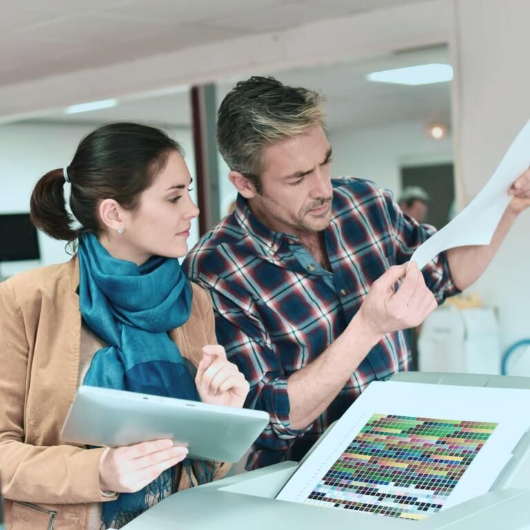 Two colleagues reviewing color swatches and a print proof in an office.