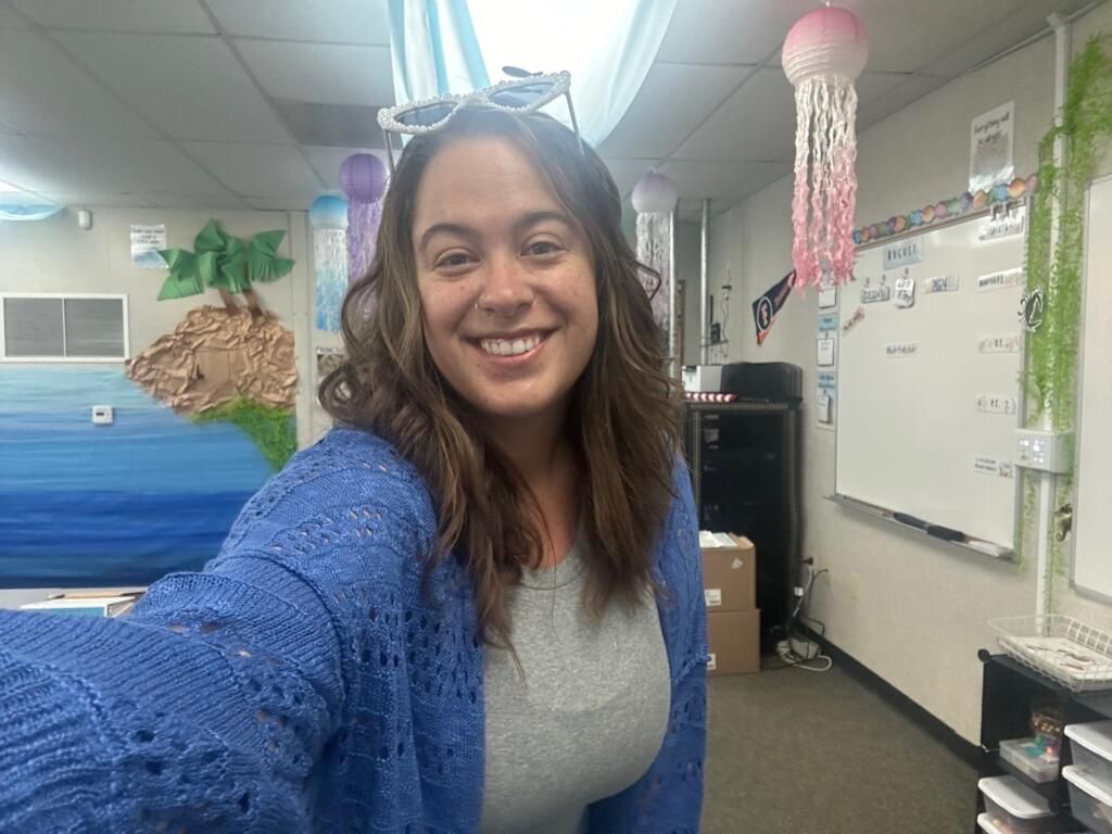 Smiling woman taking a selfie in an office with ocean mural and hanging decorations