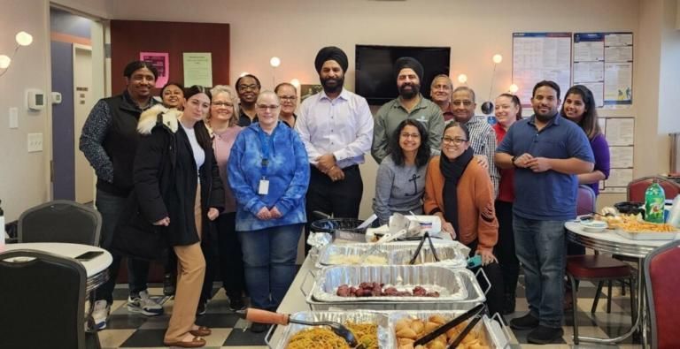 Group of people smiling at a buffet table in an office break room