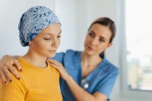 Nurse comforting a patient wearing a blue headscarf in a clinic room