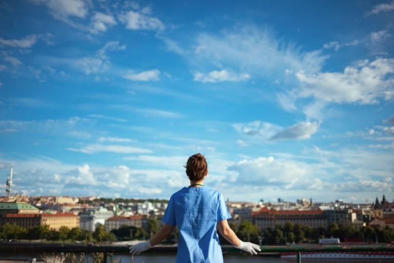 Person in a blue shirt overlooking a city skyline under a bright, cloudy sky