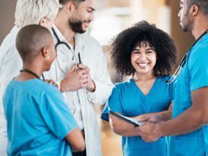 Healthcare team in blue scrubs and white coats talking together in a hospital setting