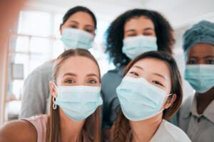 Five masked healthcare workers posing together in a clinic