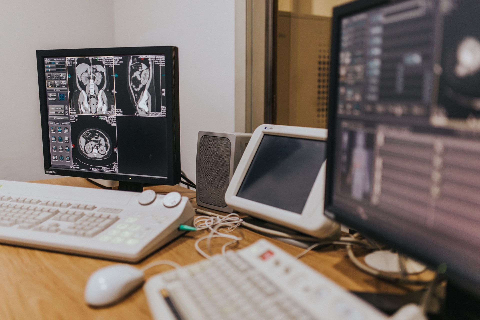 Medical imaging workstation with monitors, keyboard, and tablet on a desk