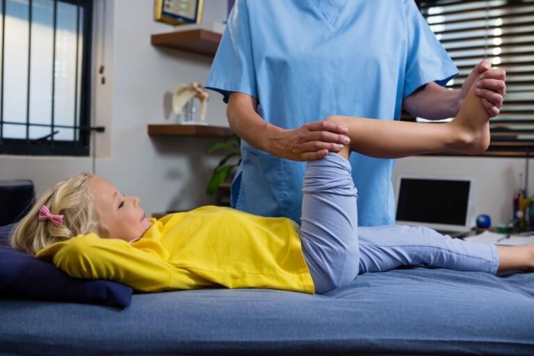 Physical therapist stretching a patient’s leg on a treatment table in a clinic