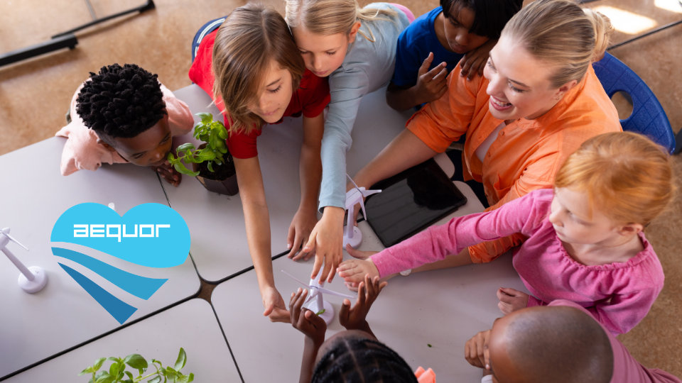 Students reaching hands together over a classroom table in a teamwork activity