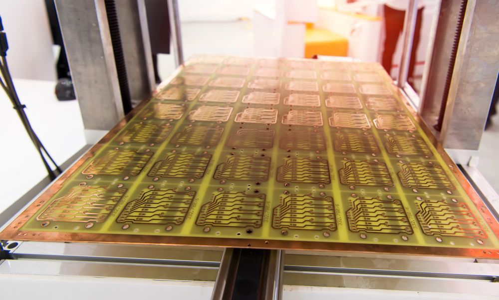 Gold-colored printed sheets on a large press machine in a workshop