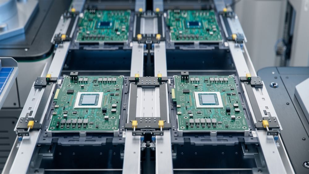 Circuit boards on a manufacturing line, green with silver processors, being transported.