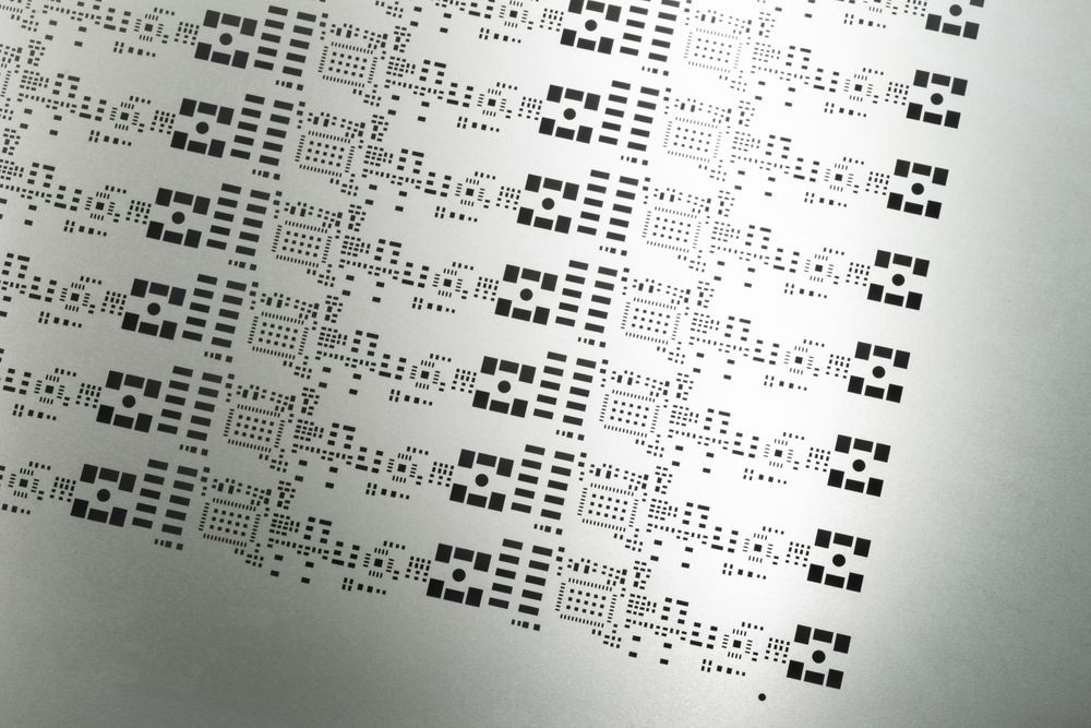 Sheet metal with repeating black patterns etched into its surface.
